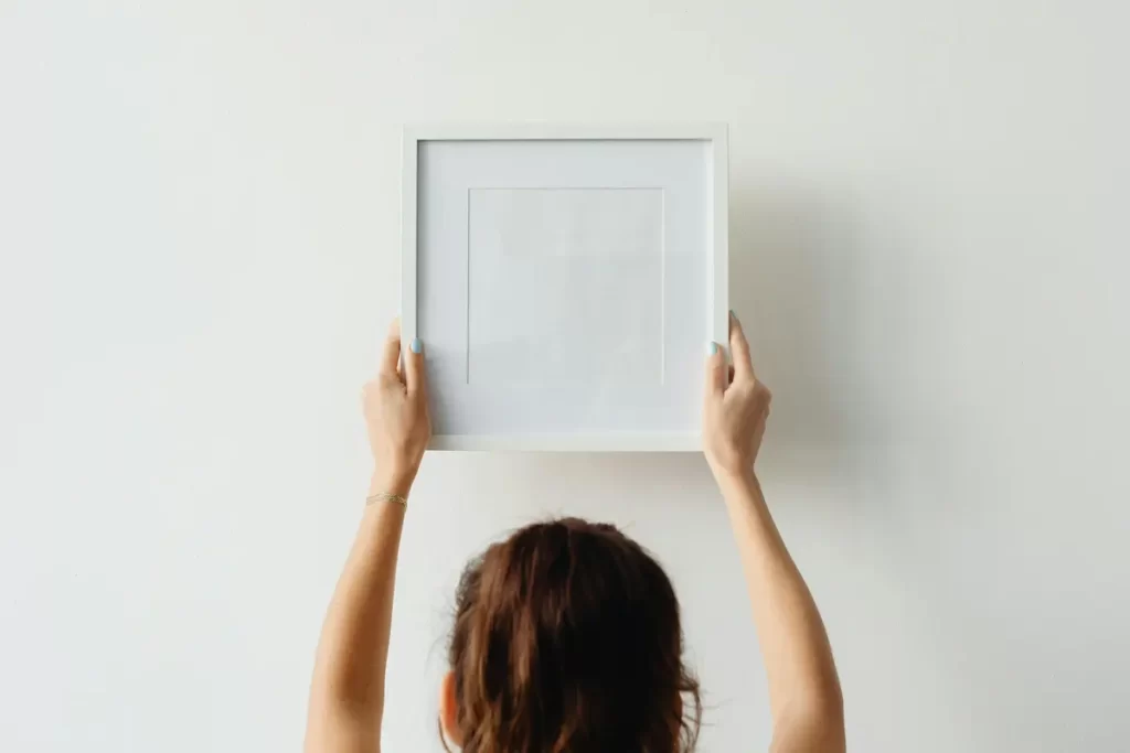 Femme qui met un cadre sur un mur blanc